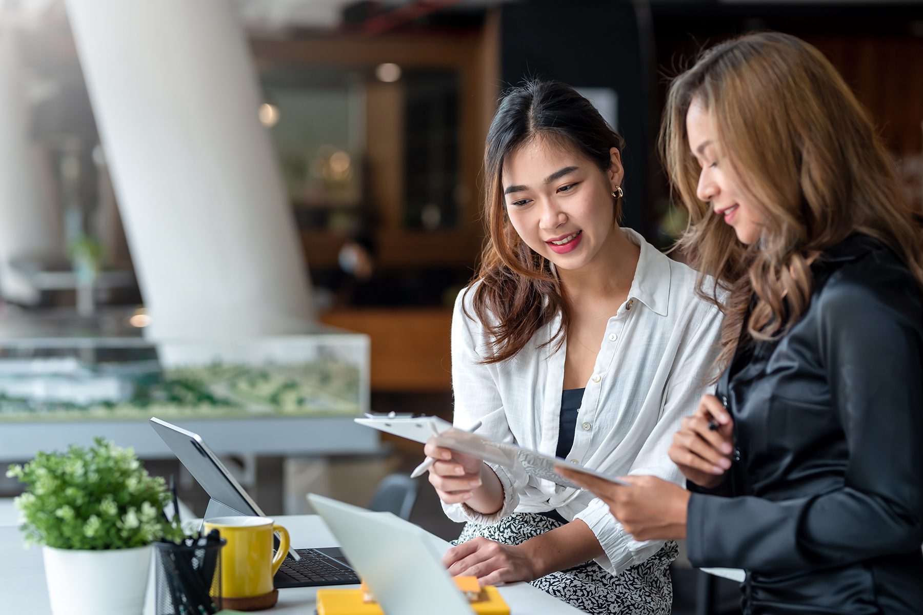Two women discussing transparent web package pricing in office